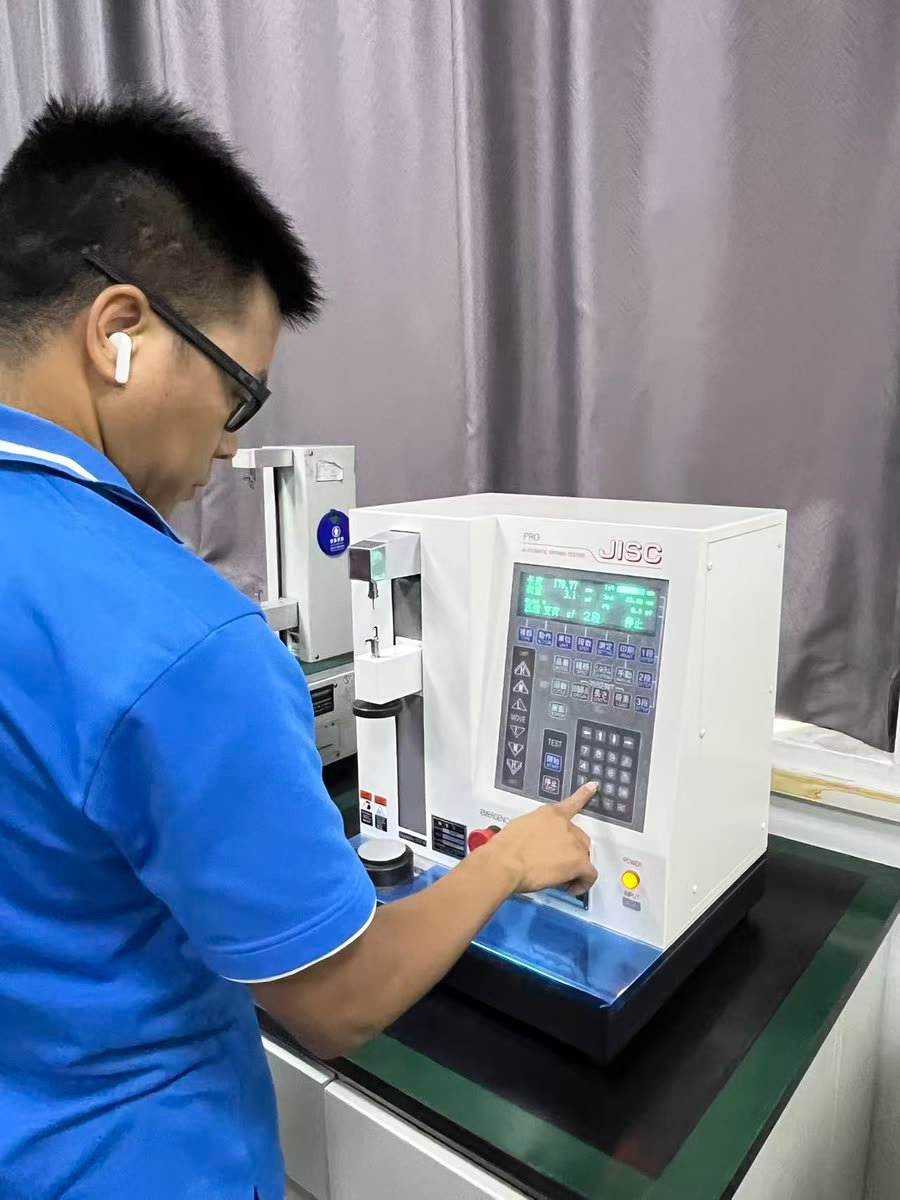 Technician testing extension spring load on an automatic spring tester in Rayong